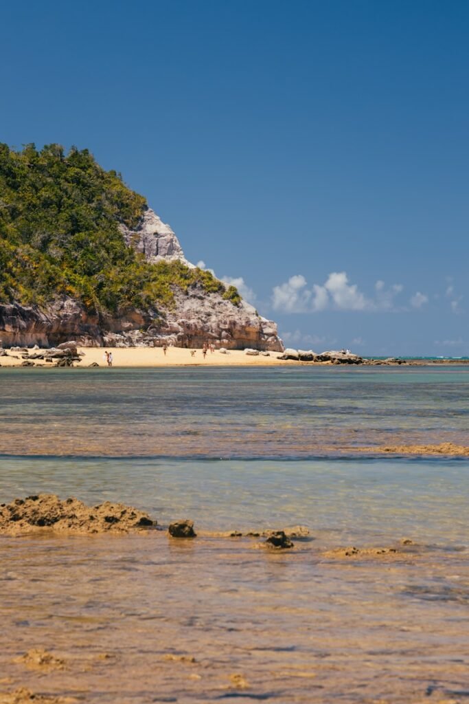 a beach with a large rock cliff Praias