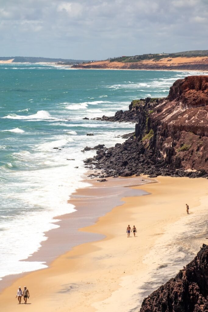 a group of people riding horses down a beach Praias